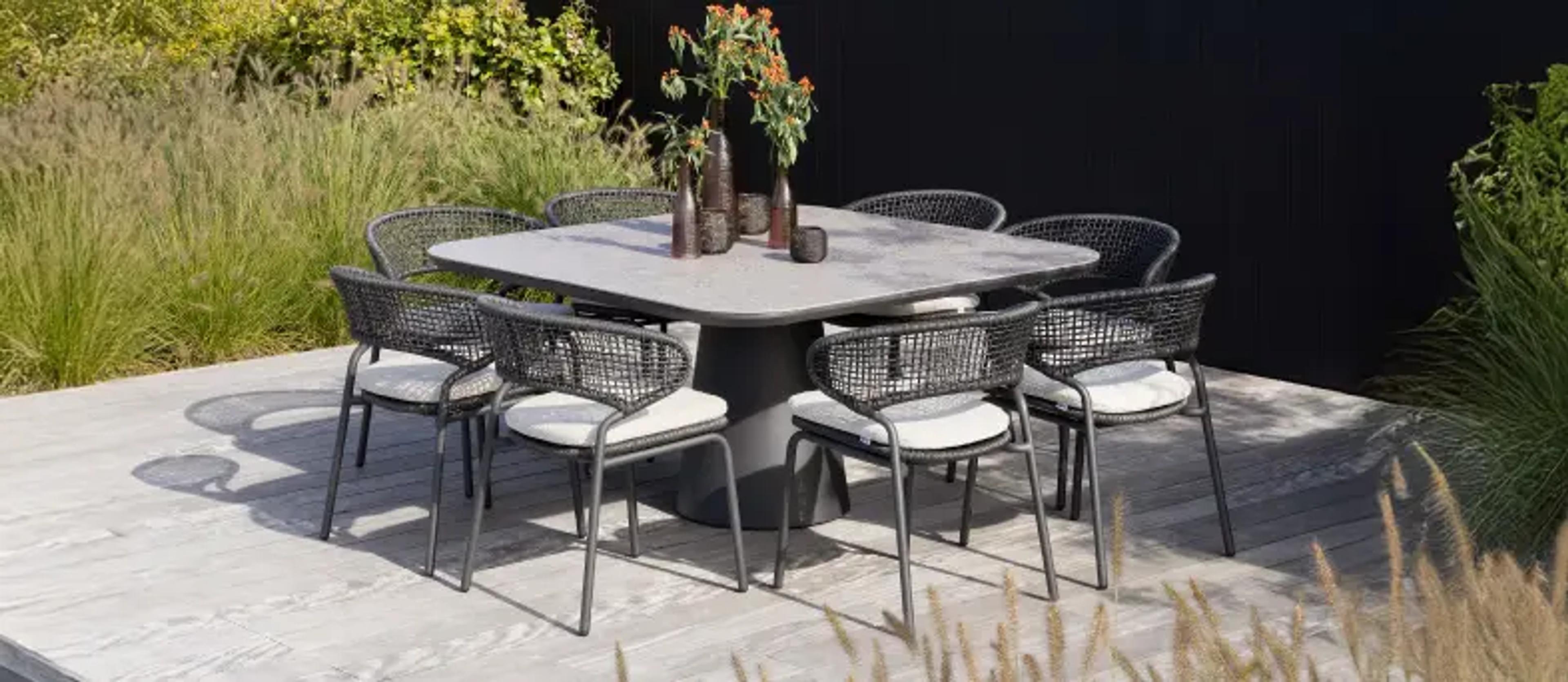 Een vierkante tuintafel met 8 tuinstoelen in de zon van exterioo tuinmeubelen
