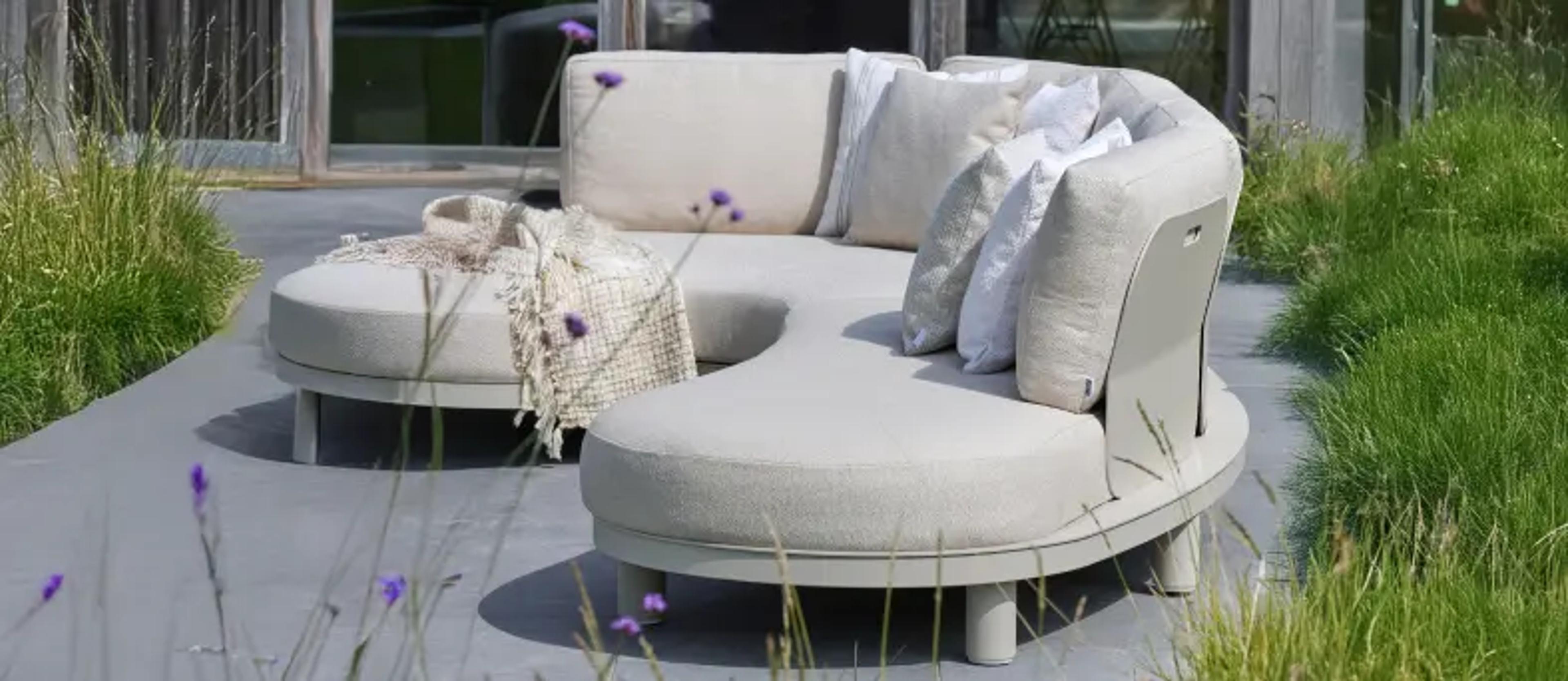 Een beige lounge van exterioo tuinmeubelen op een zonnig terras