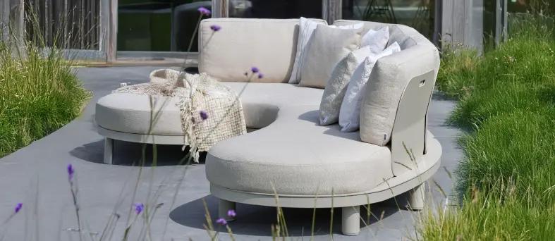 Een beige lounge van exterioo tuinmeubelen op een zonnig terras