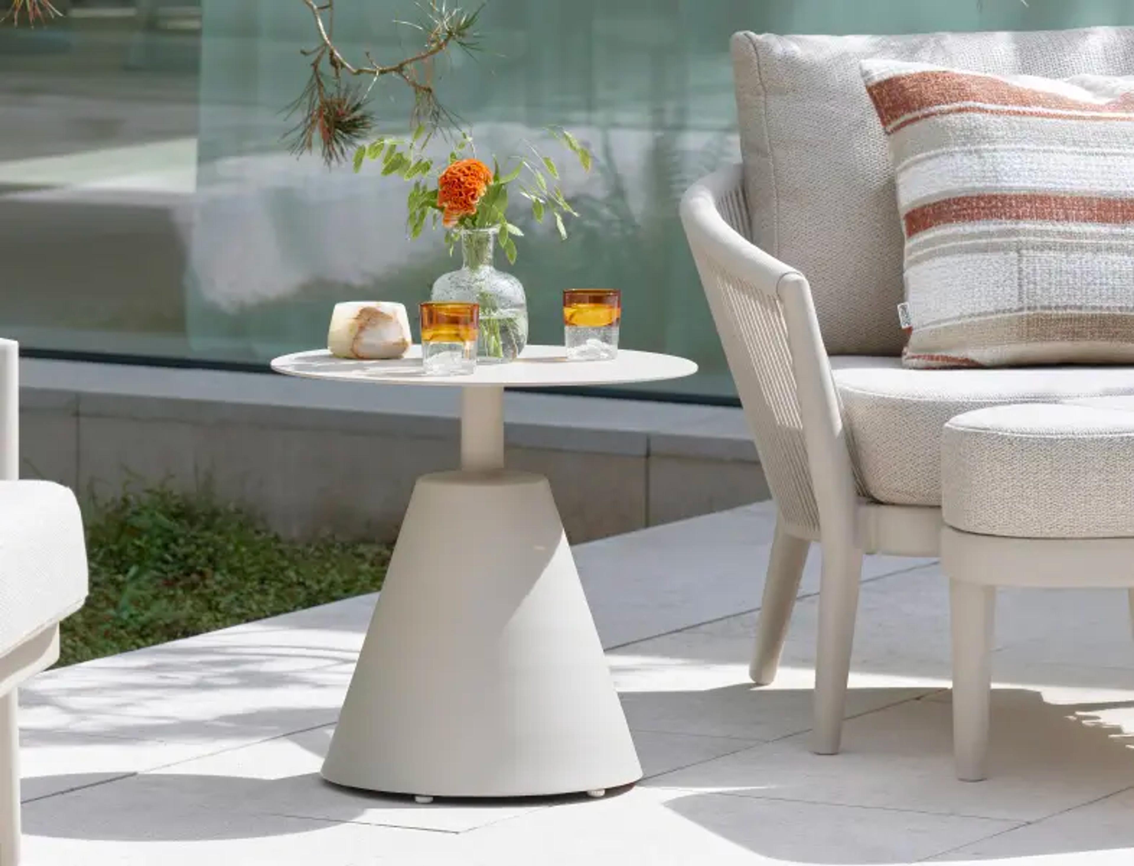 Une table d’appoint en aluminium beige sur une terrasse