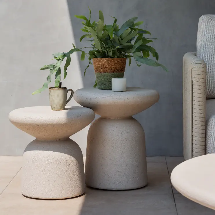 Twee betonnen bijzettafels naast een lounge van exterioo