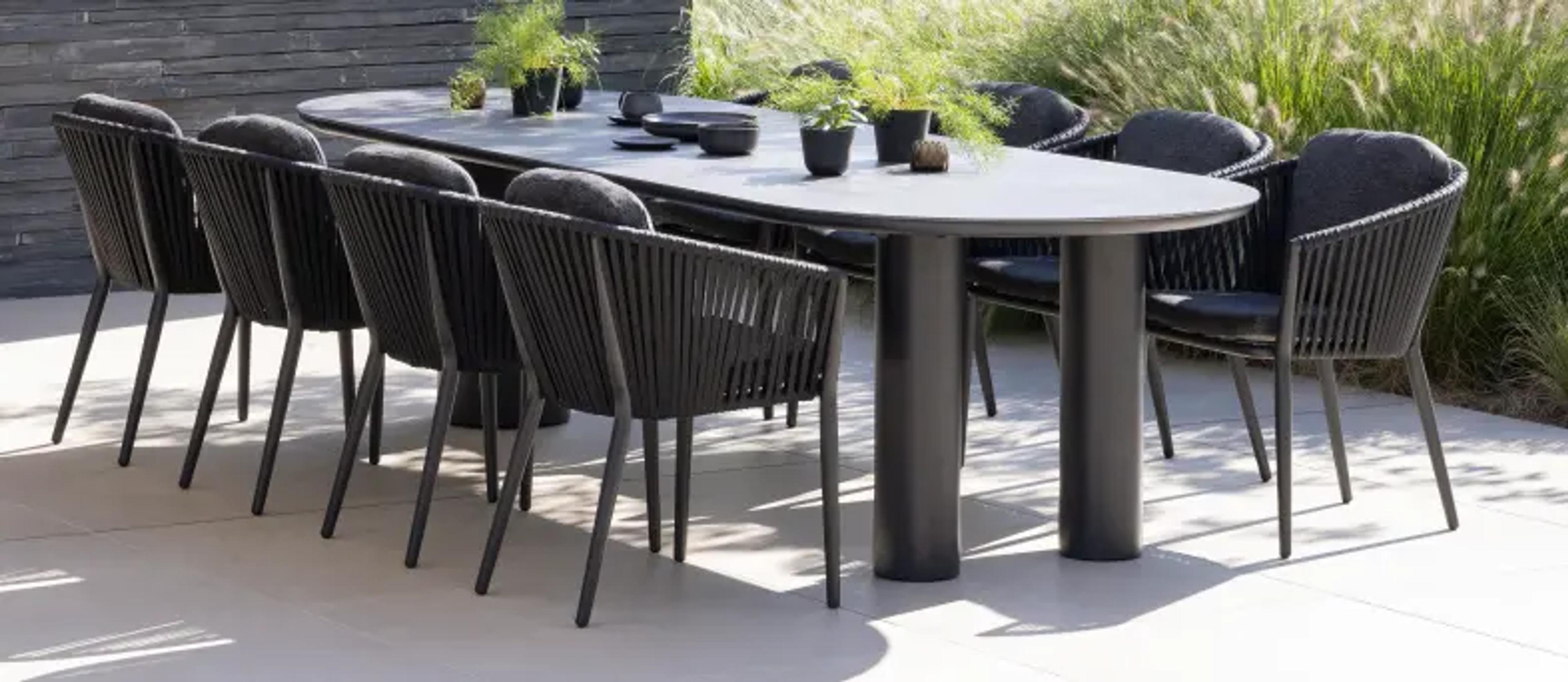Een grote tuintafel op een zonnig terras met een (plat) ovaal tafelblad van exterioo tuinmeubelen 