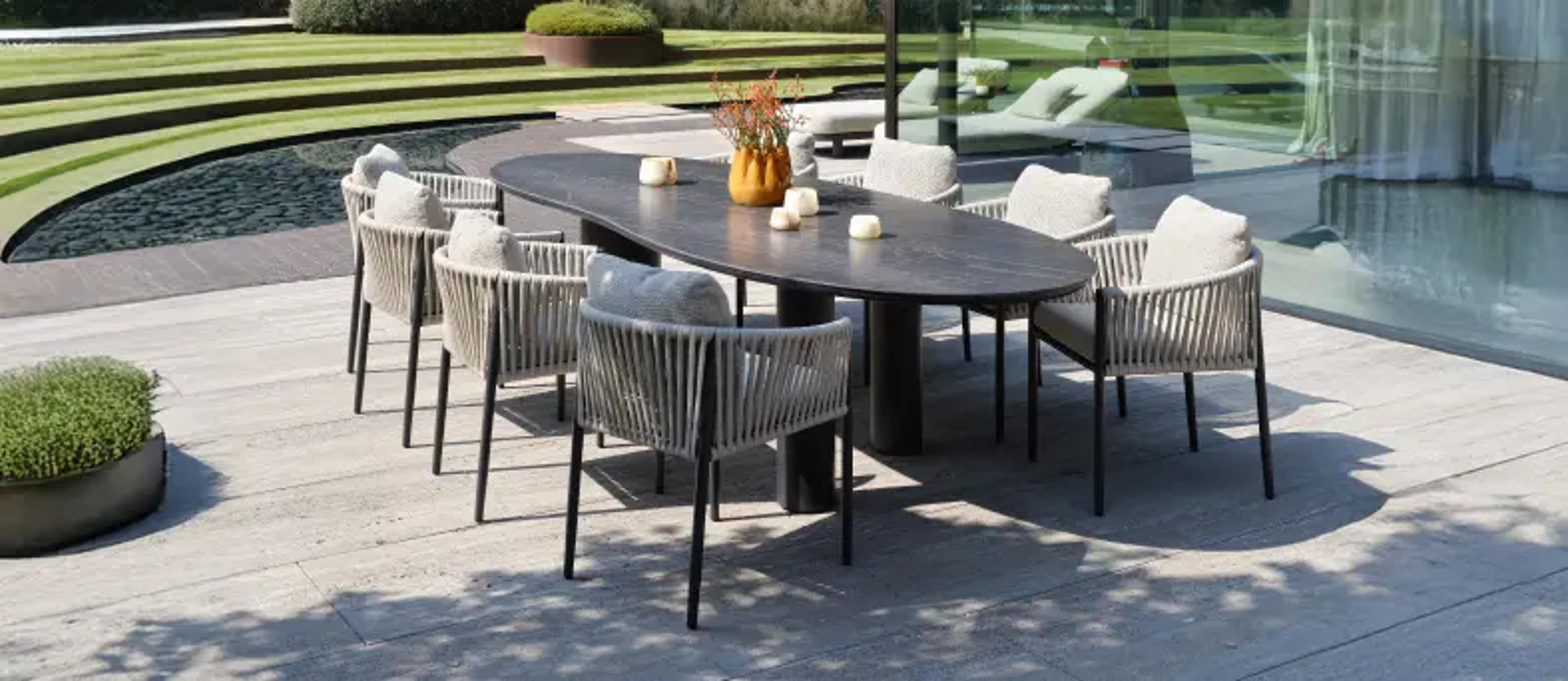 Terrasse d’été avec table de jardin en céramique et chaises en rope de la collection « Bristol à la carte » par Exterioo meubles de jardin.