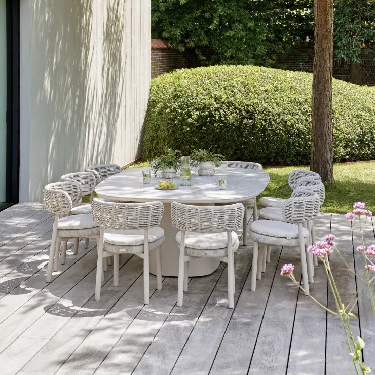 Een grote exterioo tuintafel met 10 tuinstoelen rond op een zonnig terras