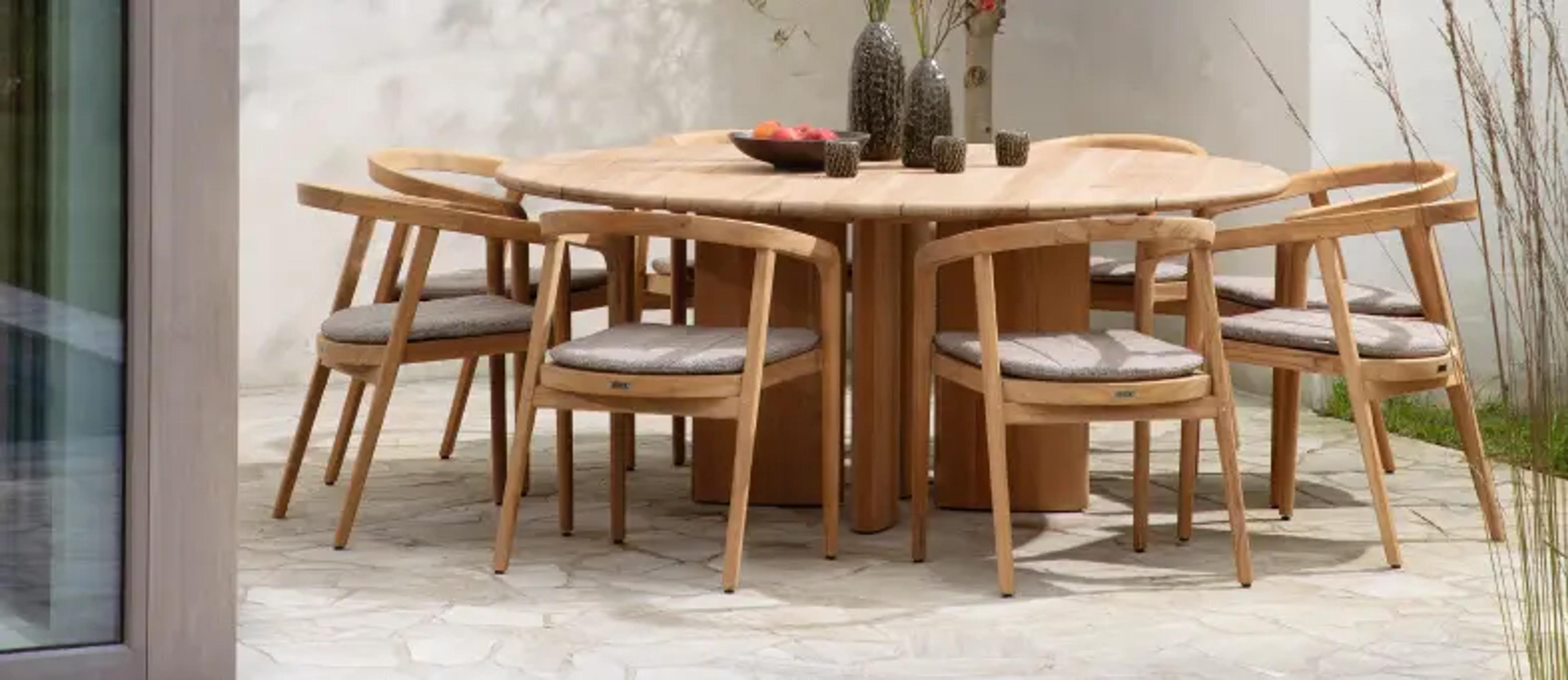 Een ronde teak tafel met 8 teak stoelen rond van exterioo tuinmeubelen