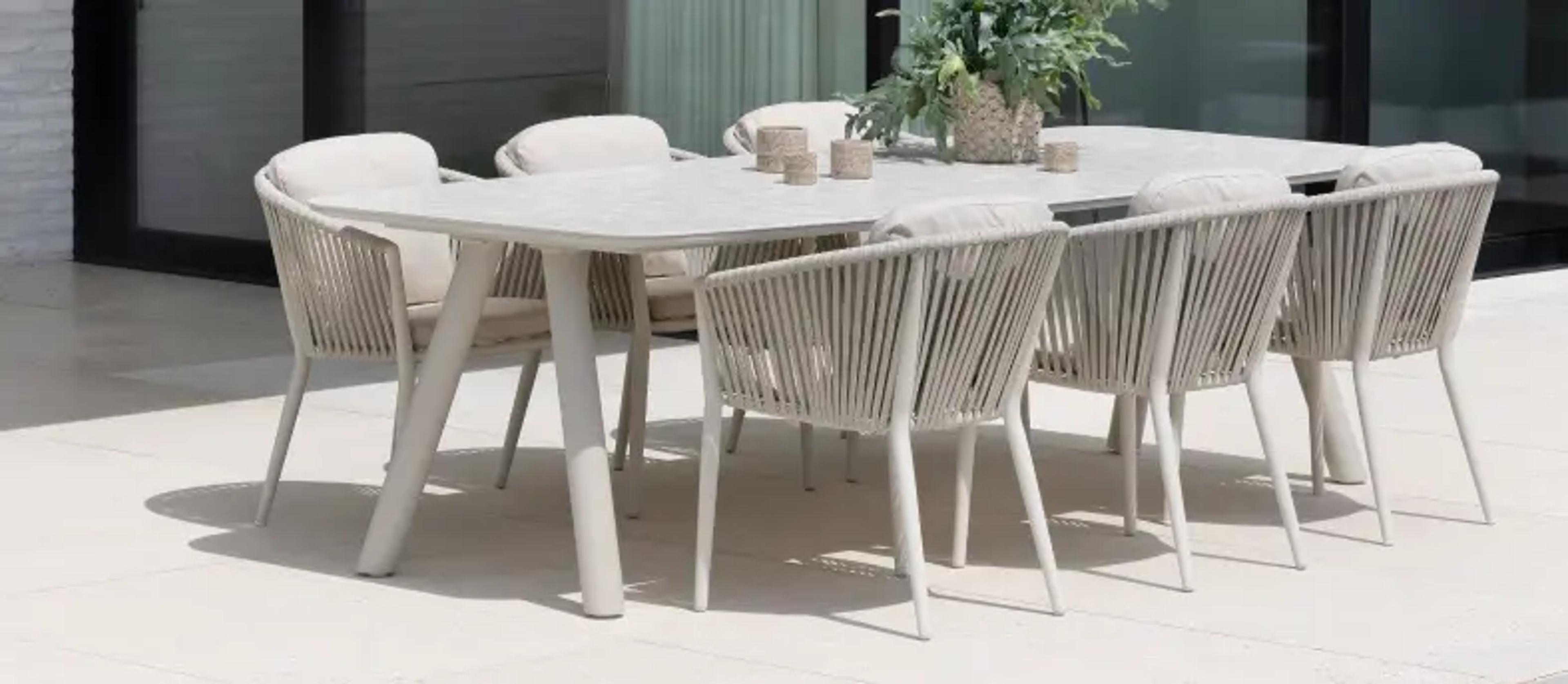 Een grote beige tuintafel met keramische blad en 6 stoelen van exterioo tuinmeubelen